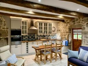 a kitchen with white cabinets and a wooden table at Maison de Bois Royale in Royère-de-Vassivière
