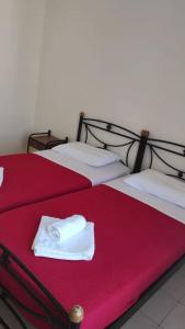 two beds with red sheets and a white towel on them at Bay's in Spetses