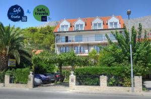 a large building with cars parked in a parking lot at Pansion Begic in Omiš