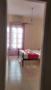 een slaapkamer met een bed met een rode deken en een raam bij Bay's in Spetses