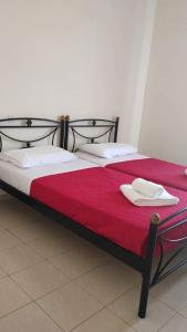 ein Bett mit roter Bettwäsche und weißen Handtüchern darauf in der Unterkunft Bay's in Spetses