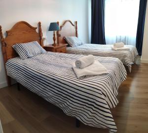 two beds in a bedroom with towels on them at CARMELA in Santiago de Compostela