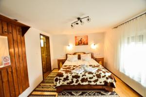 a bedroom with a bed with a cow blanket at Gyongyver Panzio in Sfântu-Gheorghe