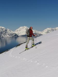 un hombre esquiando en la nieve junto a un lago en Magic Mountain Lodge - Lyngen, en Lyngseidet