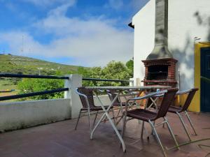 una mesa y sillas en un balcón con chimenea en Montejunto Villas - Casa do Plátano en Cadaval
