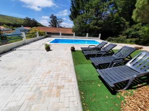 un grupo de sillas sentadas junto a una piscina en Montejunto Villas - Casa do Plátano en Cadaval