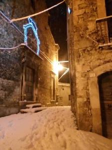 a snow covered street with a building with a neon sign at IL PIACERE DELLA NATURA in Cansano