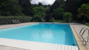 una gran piscina azul con sillas y árboles en Chez Sally et Mario, en Arnage