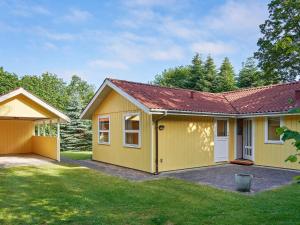 una casa amarilla con techo rojo en 6 person holiday home in L gst r en Trend
