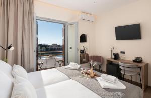 a hotel room with a bed and a desk and a window at Amphitrite Hotel in Chania