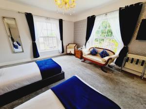 a bedroom with two beds and a chair and a chandelier at Beaufort Lodge - Central Location & Free Parking in Taunton