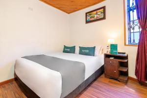 a bedroom with a large white bed and a window at Ayenda Casa Candilejas in Bogotá