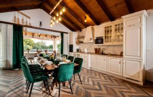 a kitchen and dining room with a table and green chairs at Luxury Villa Nature with heated private pool, sauna & fire pit, a short walk to the beach in Milna