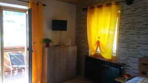 una camera da letto con tende gialle e una TV su una finestra di Huatscher a Camporosso in Valcanale
