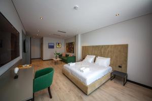 a bedroom with a large bed and a green chair at Apart-Hotel Lili2 in Sarandë