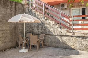 a table and chairs with an umbrella and stairs at Apartment Belman in Igalo