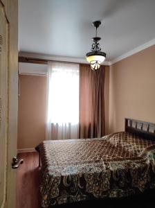 a bedroom with a bed with a window and a chandelier at 3-х ком квартира под ключ, Гагра in Gagra