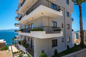 a white building with balconies next to the ocean at Apart-Hotel Lili2 in Sarandë