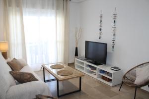 sala de estar con sofá y TV en Apartamento El Faro Leisure Port, en Estepona