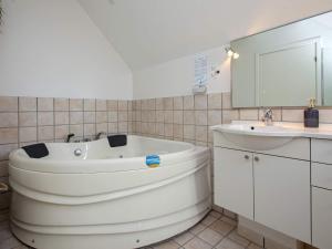 a white bathroom with a tub and a sink at 6 person holiday home in V ggerl se in Marielyst