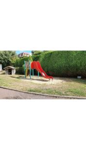 einen Spielplatz mit einer roten Rutsche in einem Park in der Unterkunft Appartement avec piscine, 100m plage et hypercentre in Cabourg