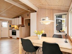 comedor y cocina con mesa de madera y sillas en Three-Bedroom Holiday home in Sæby 4, en Nordost
