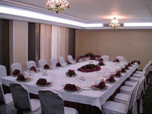 una mesa larga en una habitación con mesas y sillas blancas en Santiago, en Linares