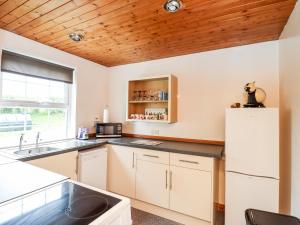 een keuken met witte kasten en een witte koelkast bij Rose Cottage in Stranraer
