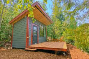 a tiny house with a deck in the woods at Woodland Cabins Micro Resort in Sorrento