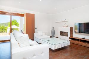 ein Wohnzimmer mit weißen Möbeln und einem Flachbild-TV in der Unterkunft Casa Fenix in Ses Paisses