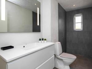 ein Badezimmer mit einem weißen Waschbecken und einem WC in der Unterkunft 6 person holiday home in L kken in Løkken