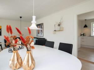 una mesa de comedor blanca con 2 jarrones con flores en 6 person holiday home in L kken en Løkken