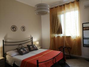1 dormitorio con 1 cama con manta roja y ventana en b & b Jasmine, en Santa Teresa di Riva