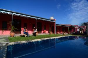 Dos personas sentadas en sillas junto a una casa con piscina en Como Entonces en Uribelarrea
