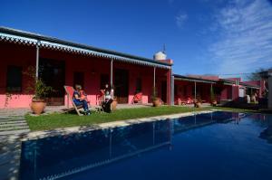 two people sitting in chairs next to a house with a pool at Como Entonces in Uribelarrea