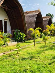 una casa con techo de hierba y algunos árboles en Tropical Sunday Bungalow - Surf And Stay, en Selong Belanak