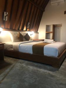 Un dormitorio con una cama grande con sábanas y almohadas blancas. en Tropical Sunday Bungalow - Surf And Stay, en Selong Belanak