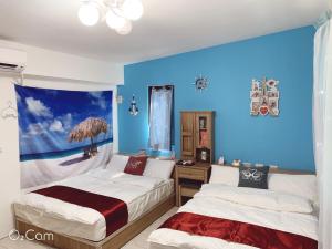 two beds in a room with blue walls at 星動小屋民宿 in Sanxing
