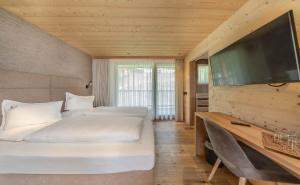 a bedroom with two beds and a flat screen tv at Nature Hotel Delta in Colfosco