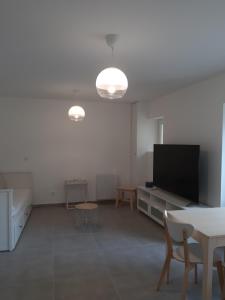 a living room with a flat screen tv and a table at Appartement Grabels 2 à 4 personnes in Grabels