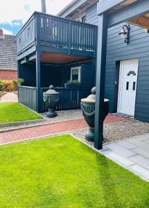 a blue house with a balcony and a yard at Rosenhof-Lodge in Hanerau-Hademarschen