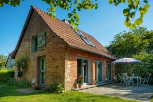 a brick house with a patio and an umbrella at Modernes Landhaus mit Sauna in Hohen Pritz