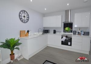 a kitchen with white counters and a clock on the wall at Luxury Central Self Contained Flat by CozyNest in Reading