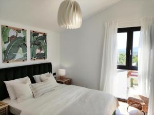 Schlafzimmer mit einem weißen Bett und einem großen Fenster in der Unterkunft Lazy 8 Villa in Garica