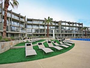 a row of lounge chairs on a lawn in front of a building at Resort Apartment 109 in Torquay