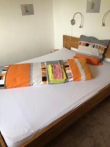 Una cama blanca con mantas y almohadas coloridas. en Nid d'abeilles, en Tramelan