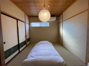 ein Zimmer mit einem Bett in der Ecke mit einer Leuchtvorrichtung in der Unterkunft 吹屋庵 in Takayama