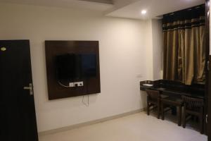 a room with a tv and a table and chairs at Hotel The Black Gold in Chandīgarh