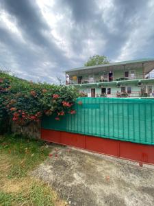 ロオにあるRostovchanka Guest Houseの花の囲い付き緑赤の建物