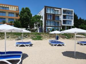 Un grupo de sillas y sombrillas en una playa. en AMARA-BOUTIQUE & DESIGN - Студио, en Ravda